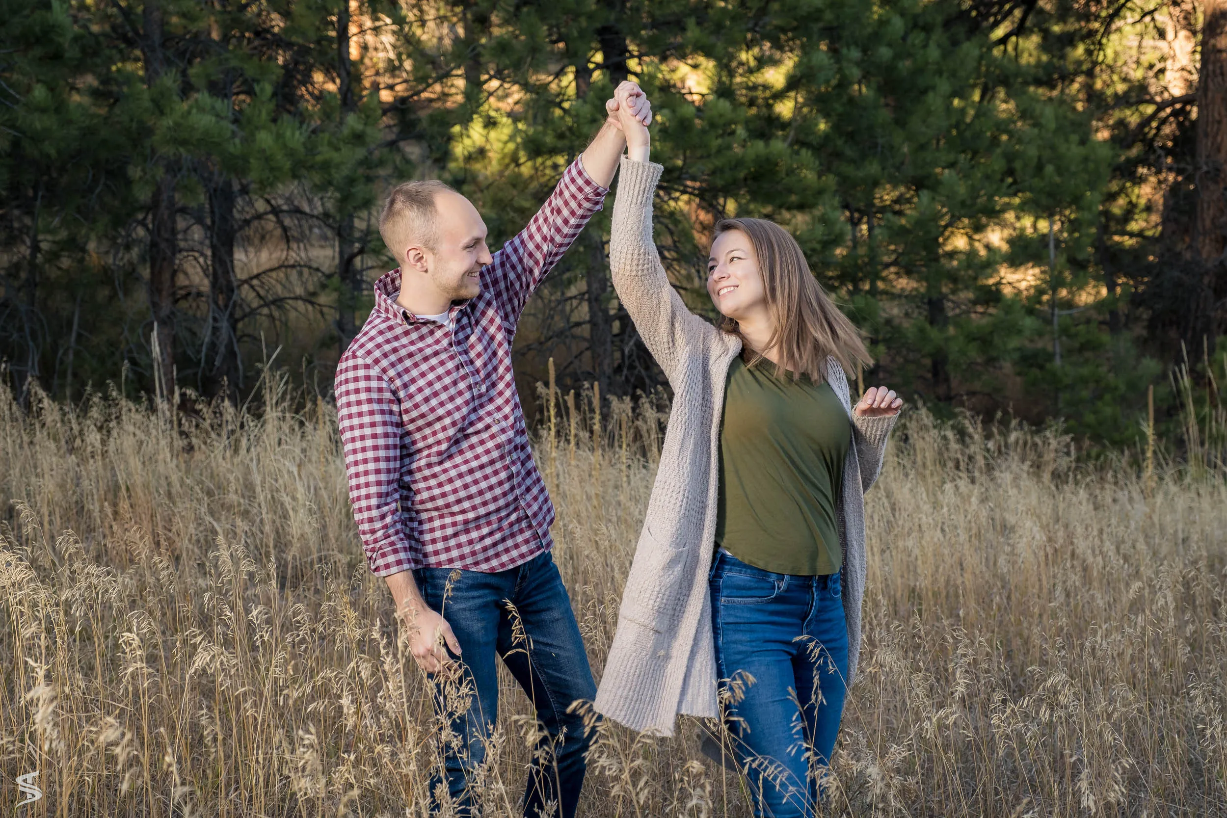 A couple laughing and dancing in a sunlit meadow