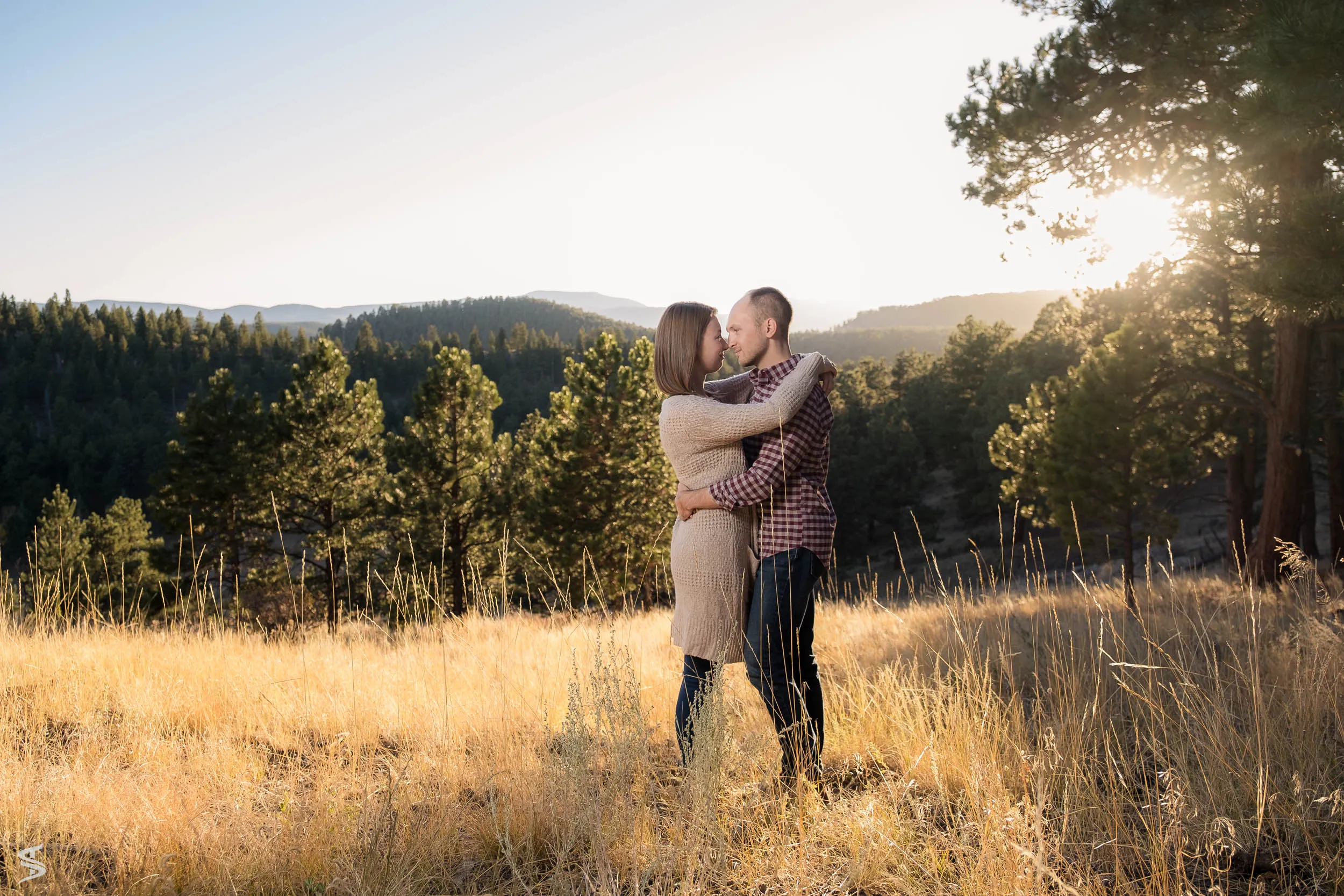 A couple embracing in an open field at golden hour