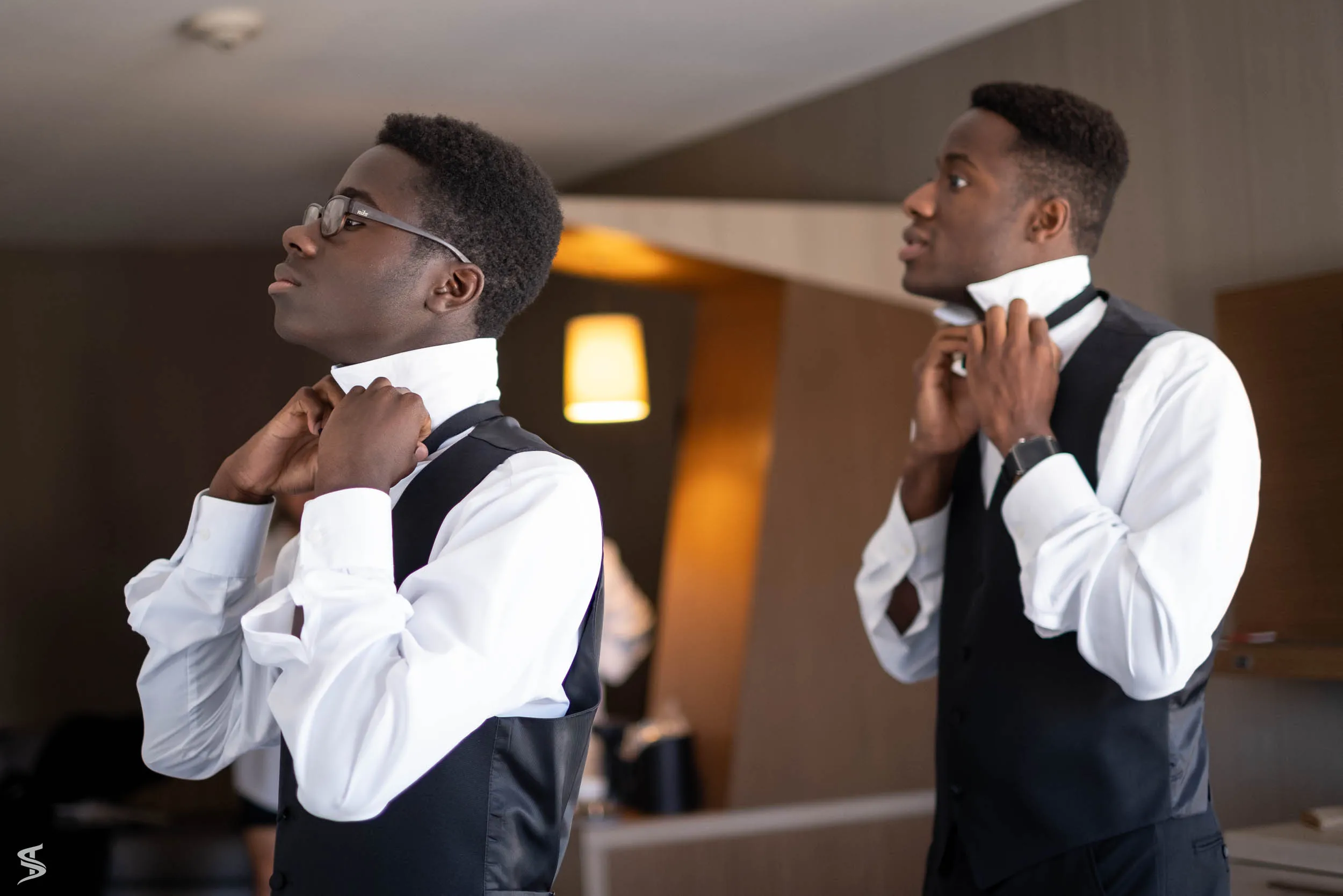 Two men adjusting their bow ties while getting ready for a destination wedding.