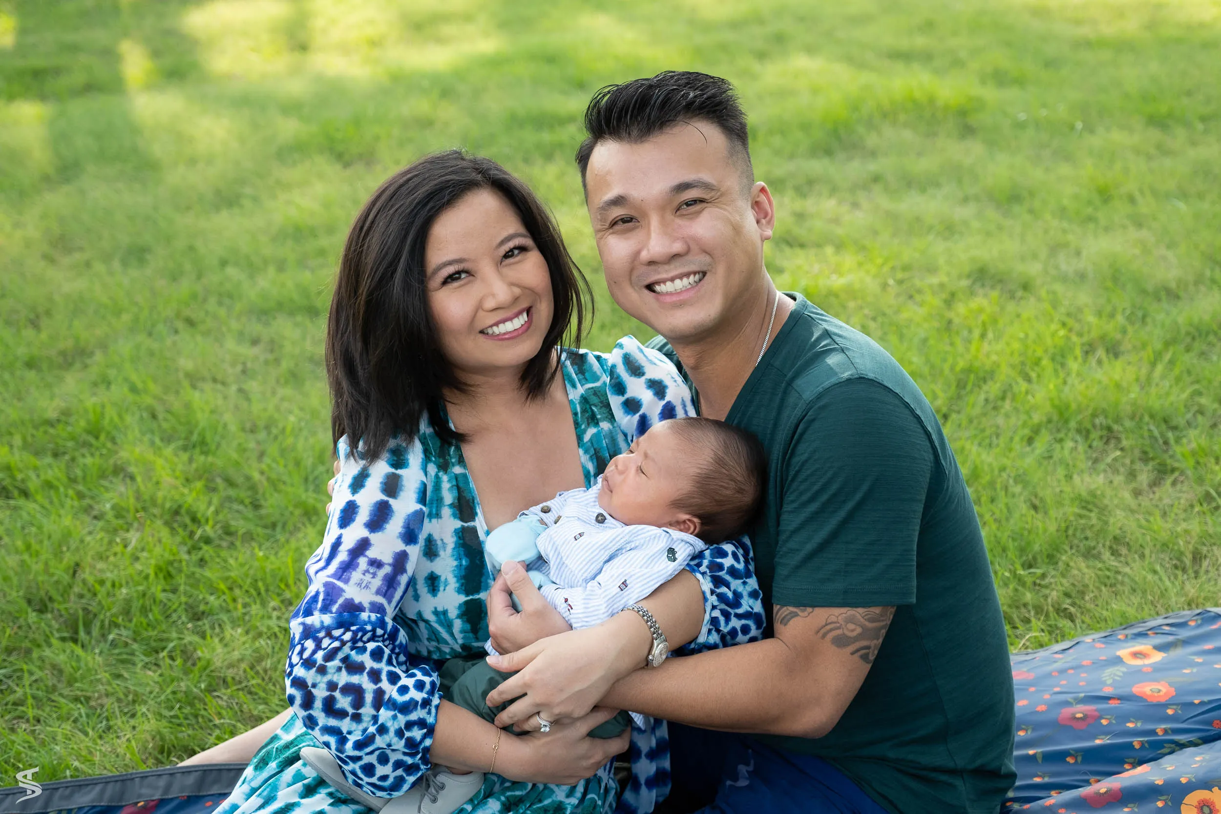 Parents cuddling their newborn in a green park